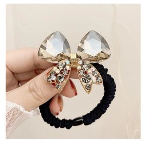 Detail view of brown crystal bow hair tie with sparkling rhinestones and black elastic band