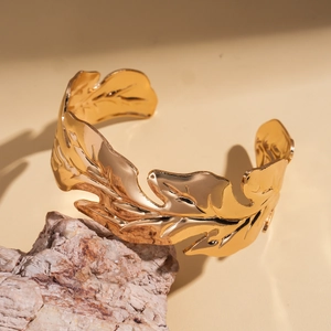 Macro detail of golden leaf-shaped cuff bracelet with intricate metal vein textures