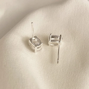 Macro shot of silver 925 sterling silver oval cubic zirconia stud earrings on linen cloth