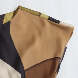 Detail of elegant satin-textured dress showing patchwork print and fine shoulder stitching