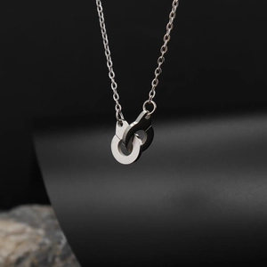 Macro view of minimalist handcuffs pendant in silver stainless steel on a dark background