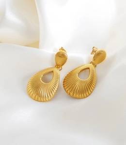 Detail of 18K gold teardrop earrings with textured stripes on white silk background