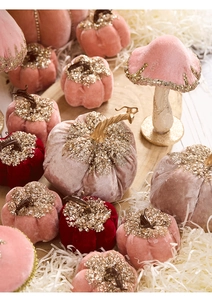 Detail of pink and burgundy velvet pumpkins and mushrooms with gold glitter on wood