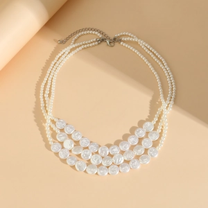 Detailed view of triple-layered pearl necklace with large flat pearls and silver lobster clasp