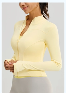 Side view of a tight pale yellow yoga jacket with a high collar and zipper details