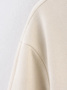 Close-up of premium beige suede jacket fabric showing detailed stitching and texture
