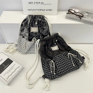 Detail of drawstring backpack showing marble print and plaid patchwork with thick cotton rope