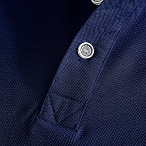 Detail of navy blue polo shirt showing piqué fabric texture and collar buttoning craftsmanship