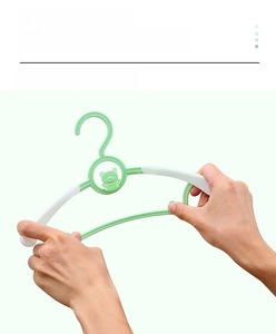 Flexible green children's plastic hanger shown bending without breaking to show durability