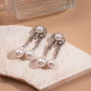 Detail of vintage silver pearl drop earrings with rhinestones on marble stone display