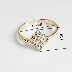 Detail view of gold adjustable ring featuring a diamond-set floral motif and carved texture