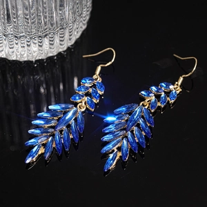 Detail shot of elegant blue leaf tassel earrings with gold metal on a dark reflective surface