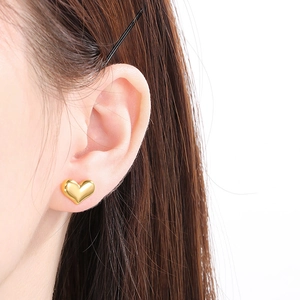 Gros plan de boucles d'oreilles cœur plaquées or 18 carats portées par un mannequin