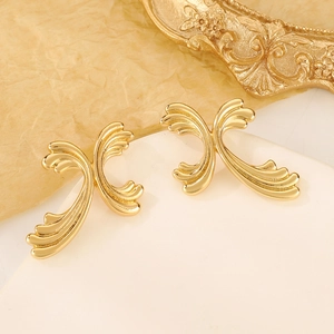 Macro shot of gold teardrop earrings with a polished surface on a white circular base