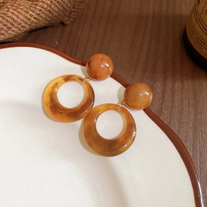 Detail view of resin amber hoop earrings with a spherical stud in a vintage aesthetic