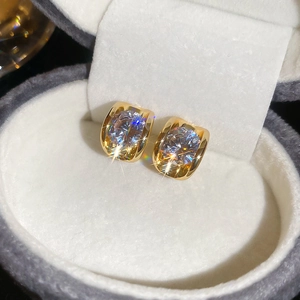 Macro shot of gold-plated stud earrings with round zircons in a gray velvet box