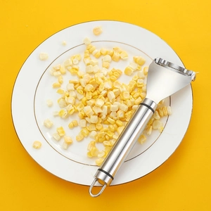 Stainless steel corn peeler tool for removing kernels on a white plate with corn