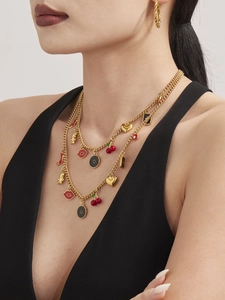Detailansicht der Vintage-Goldhalskette mit Anhängern und gedrehten Creolen an einem Model