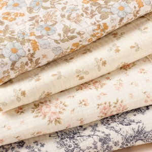 Floral cotton muslin baby blanket with fringe trim shown in stacked assorted patterns