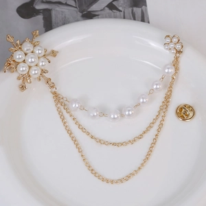 Elegant gold-tone pearl brooch featuring snowflake charms and layered tassel chains