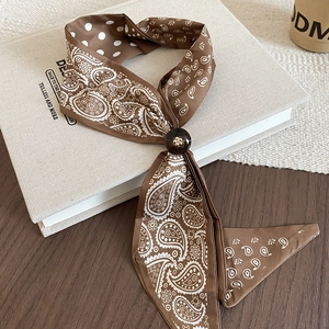 Close-up of paisley scarf necklace with dark brown wooden bead on minimalist book