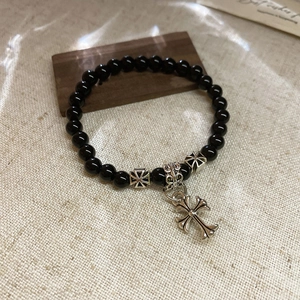 Détail macro de perles d'onyx noir avec des breloques de croix en argent vintage