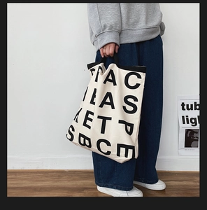 Close-up of minimalist canvas tote bag featuring bold black lettering and large capacity