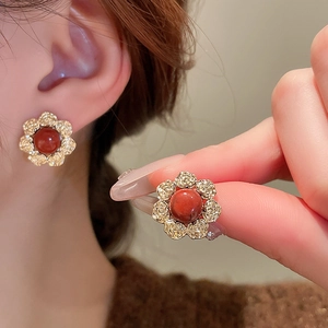 Close-up of vintage flower earrings with gold petals and reddish-brown stone inlay