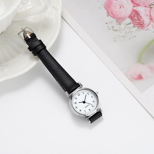 Detail shot of a small quartz watch with a black leather strap and round silver case