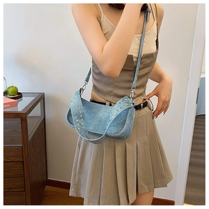 Detail of light blue denim texture shoulder bag with silver studs and metal rivets