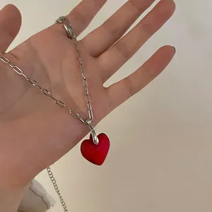 Close-up of a red heart-shaped pendant on a silver-tone geometric link chain necklace