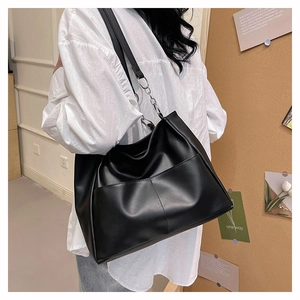 Dettaglio della borsa shopper nera con catene in metallo argento e pelle opaca liscia