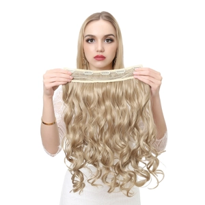 Detail view of long golden wavy hair extension with clips on a white background