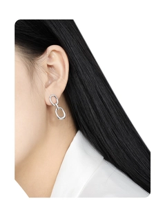 Close-up of minimalist silver geometric double loop earrings on woman's ear