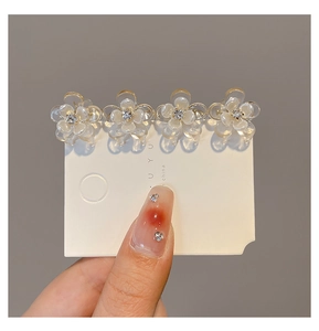 Detailed macro view of four small camellia flower hair claws with crystal center on a card