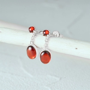 Detail view of 925 silver stud earrings featuring deep red oval ruby gemstones