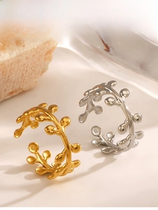 Detailed view of gold and silver leaf-shaped open rings on a natural stone base