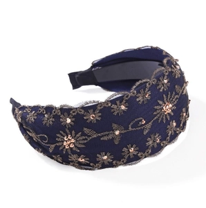 Detalle de la diadema de tela azul marino con bordado floral dorado y pedrería fina
