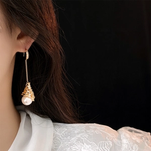 Vue détaillée de longues boucles d'oreilles dorées avec oxydes de zirconium et perle blanche