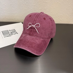 Détail de la casquette bordeaux en coton lavé avec broderie nœud blanc et aspect vintage