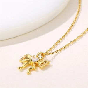 Golden stainless steel bow necklace with heart-shaped zircon pendant on white background