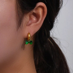 Gold plated earrings featuring a green zircon butterfly pendant worn by a model