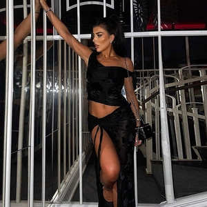 Detail of a black one-shoulder cropped top and high-slit maxi skirt with flocking texture