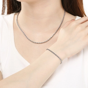 Close-up of a matching silver rope chain necklace and bracelet set on a white shirt