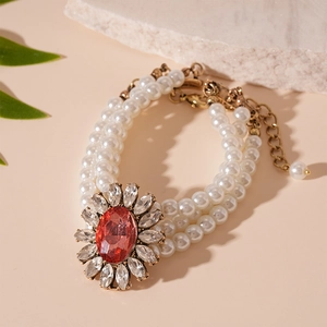Detailed view of triple-strand pearl bracelet with red gemstone floral centerpiece