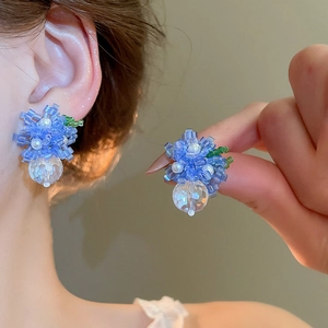 Close-up of blue beaded flower earrings with white pearls and faceted crystal pendant