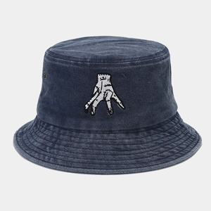Detail of embroidered hand patch on navy blue washed denim bucket hat with vintage texture