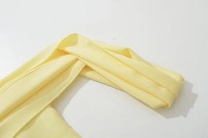 Primo piano delle cuciture fini e della trama del tessuto a maglia giallo chiaro dell'abito