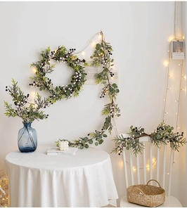 Close-up of Christmas eucalyptus garland with white berries and warm LED string lights