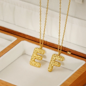 Detailed view of 18K gold plated lava textured initial pendants on O-chain in a gift box